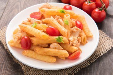 Ahşap bir masa üzerinde tavuk domates soslu Penne makarna