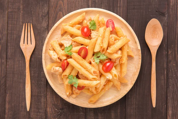 Ahşap arka plan üzerinde tavuk domates soslu Penne makarna