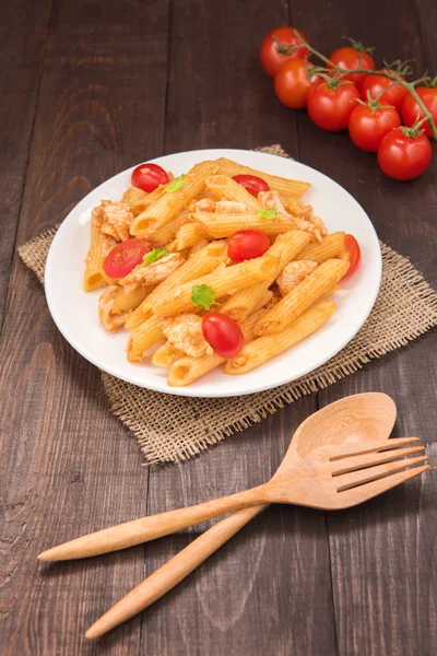 Penne pasta en salsa de tomate con pollo en una mesa de madera — Foto de Stock