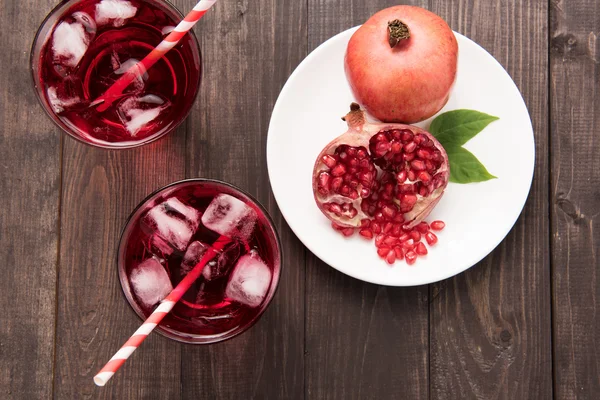 Ripe pomegranates with juice on wooden background — Stock Photo, Image