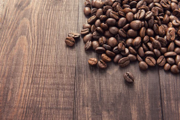 Gebrande koffiebonen op de houten achtergrond — Stockfoto
