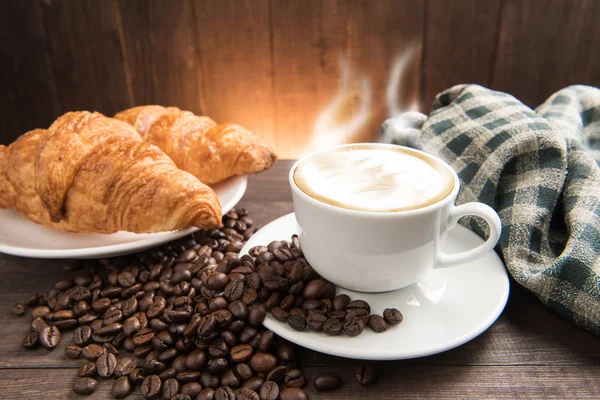 Café da manhã xícara de café e croissant no fundo de madeira — Fotografia de Stock