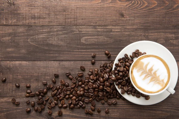 Kaffekopp och kaffebönor på trä bakgrund. Ovanifrån — Stockfoto