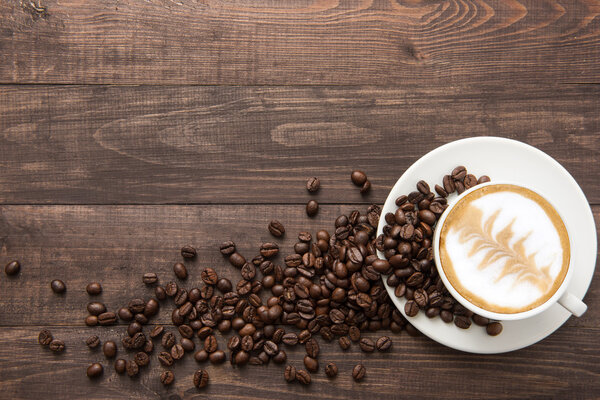 Coffee cup and coffee beans on wooden background. Top view