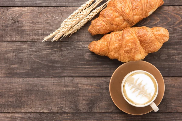 Taza de café y croissants recién horneados sobre fondo de madera. Parte superior — Foto de Stock