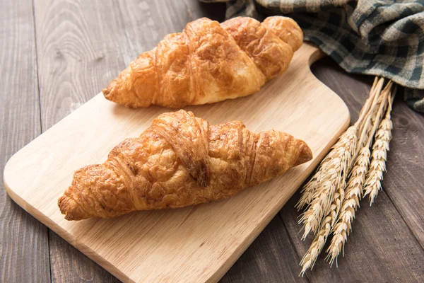 Croissant čerstvě upečený máslo na dřevěné pozadí. — Stock fotografie