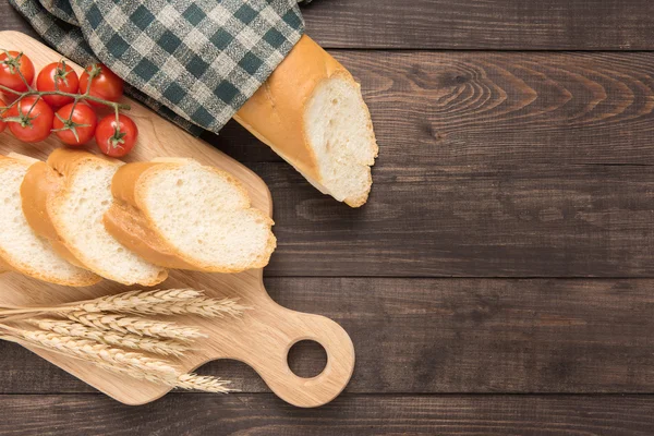 Baguete recém-assada e tomate em fundo de madeira — Fotografia de Stock