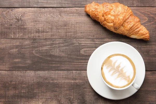 Šálek kávy a čerstvé croissanty na dřevěné pozadí. Vrchol — Stock fotografie