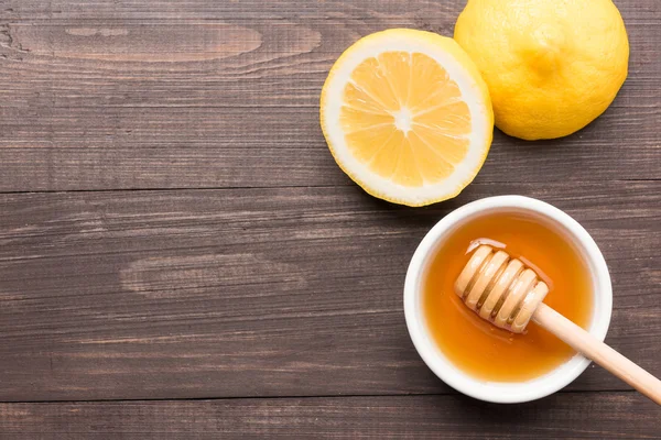 Tatlı bal ve limon ahşap masa üzerinde kase
