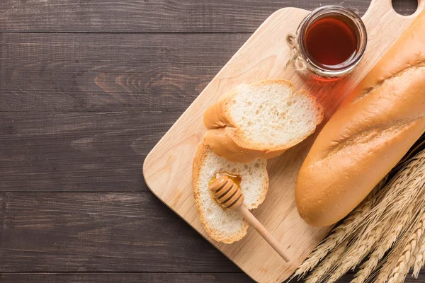 Pan rústico o baguette con miel sobre fondo de madera — Foto de Stock