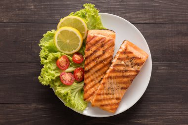 Limonlu ızgara somon, ahşap arka plan üzerinde domates