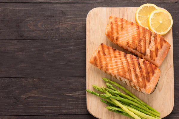 Жареный лосось и лимон, спаржа на деревянном фоне — стоковое фото