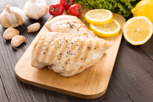 Ahşap masa üzerinde marine edilmiş ızgara tavuk göğsü