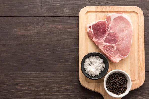 Top weergave ruwe pork chop biefstuk en zout, peper op houten CHTERGRO — Stockfoto