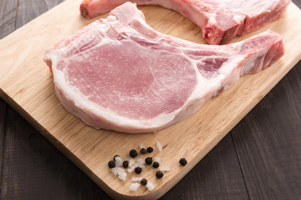 Raw pork chop steak and salt, pepper on wooden background — Stock Photo, Image