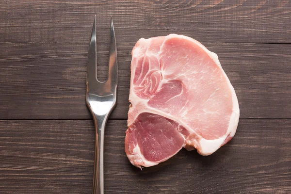 Carne asada cruda y tenedor de carne sobre fondo de madera — Foto de Stock