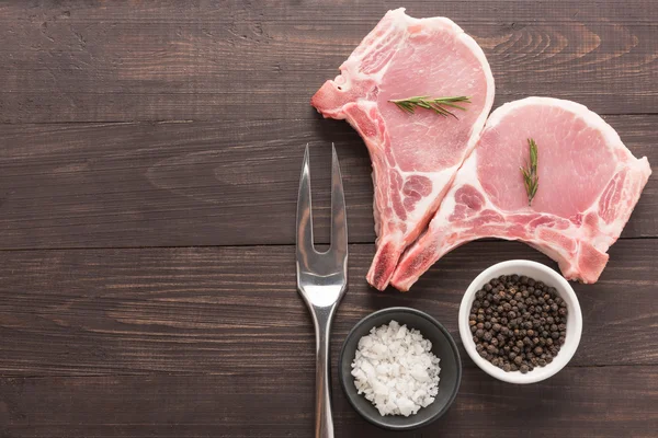 Carne asada cruda y tenedor de carne sobre fondo de madera — Foto de Stock