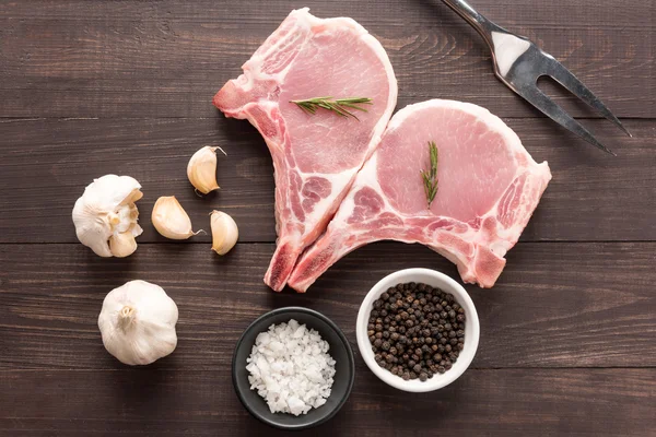 Vista dall'alto carne fresca cruda e sale, pepe, aglio, forchetta di carne su w — Foto Stock