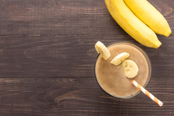 Ahşap arka plan üzerinde muz smoothie. Üstten Görünüm