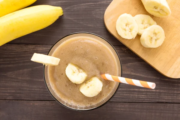 Ahşap arka plan üzerinde muz smoothie. Üstten Görünüm