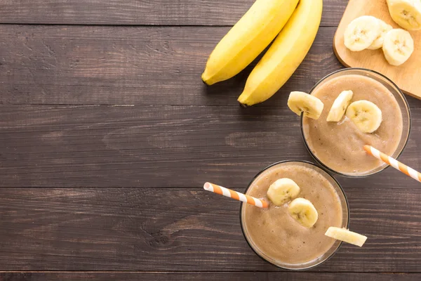 Üst muz smoothie ahşap arka plan üzerine vurdu.