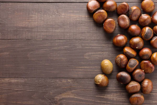 Deliciosas castanhas assadas no fundo de madeira — Fotografia de Stock