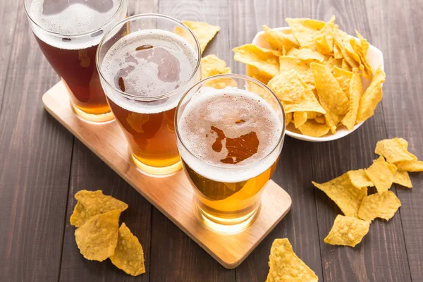 Assortiment van bierglazen met nachos chips op een houten tafel — Stockfoto