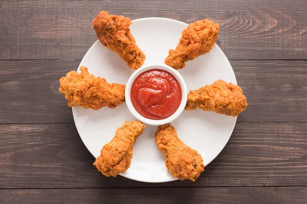 Podudzie kurczaka smażone i ketchupem na drewniane tła — Zdjęcie stockowe