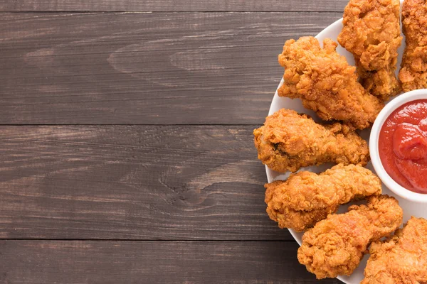 Gebakken kip drumstick en ketchup op houten achtergrond — Stockfoto