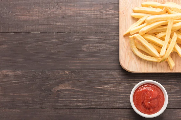 Batatas fritas com ketchup em fundo de madeira — Fotografia de Stock