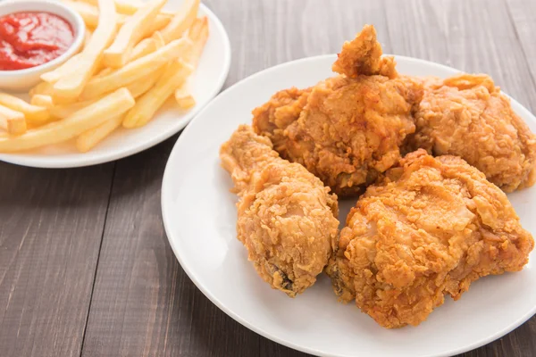 Gebakken kip en Franse frietjes op een houten achtergrond — Stockfoto