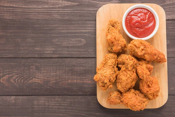 Muslo de pollo frito y ketchup sobre fondo de madera — Foto de Stock