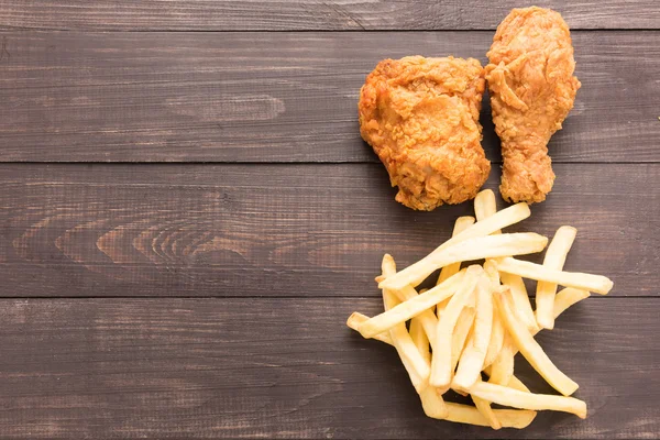 Stekt kyckling och pommes frites på trä bakgrund — Stockfoto