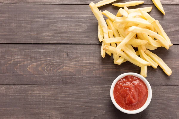 Batatas fritas com ketchup em fundo de madeira — Fotografia de Stock