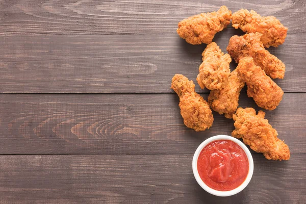 Podudzie kurczaka smażone i ketchupem na drewniane tła — Zdjęcie stockowe