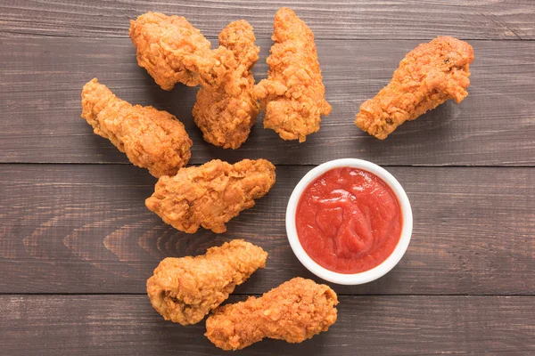 Gebakken kip drumstick en ketchup op houten achtergrond — Stockfoto