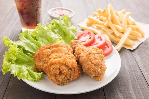 Gebakken kip en Franse frietjes op een houten achtergrond — Stockfoto