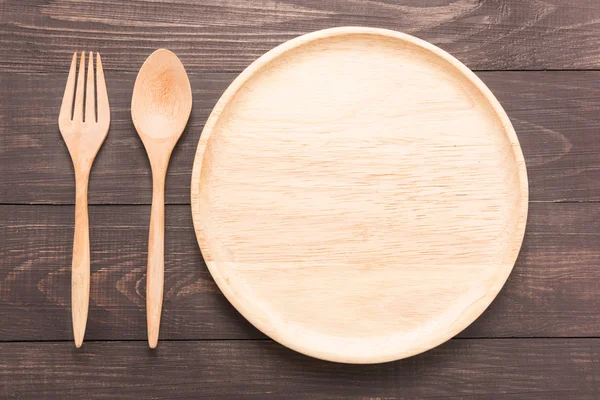 Juego de tenedor, cuchara y plato de madera sobre mesa de madera . —  Fotos de Stock