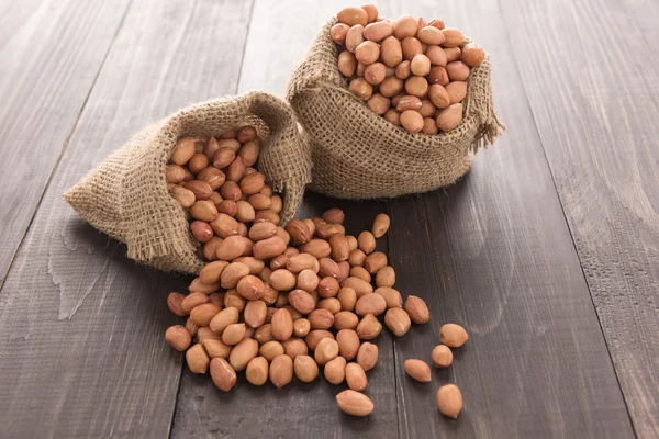 Peanut in sacks on the wooden background — Stock Photo, Image