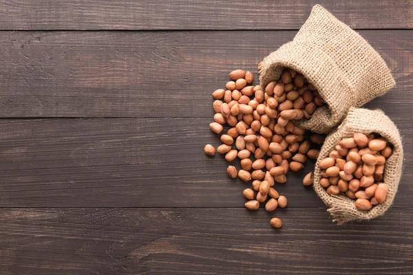 Peanut in sacks on the wooden background — Stock Photo, Image