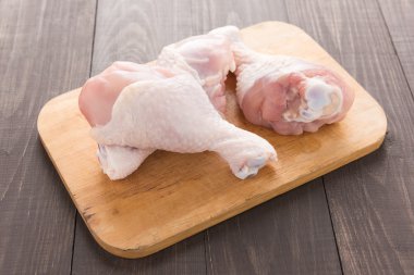 Ahşap masa üzerinde kesme tahtası üzerinde çiğ tavuk sopaları