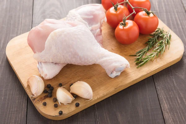 Ingredienti e cosce di pollo crudo sul tagliere su legno — Foto Stock