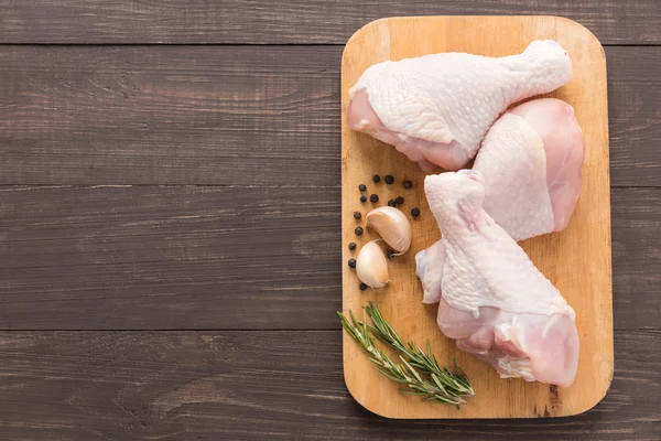 Bâtonnets de poulet cru sur planche à découper sur fond en bois — Photo