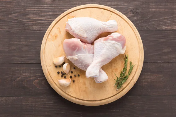 Baquetas de frango cru na placa de corte em fundo de madeira — Fotografia de Stock