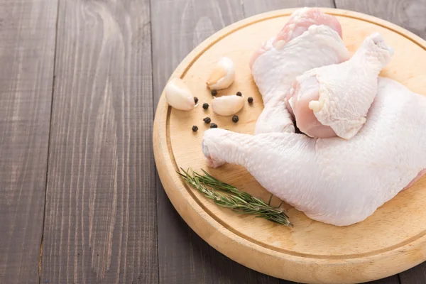 Perna de frango cru e pimenta, alho, alecrim em backgroun de madeira — Fotografia de Stock