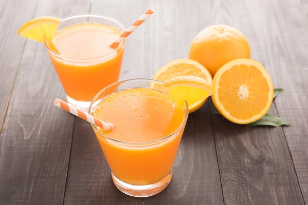 Jugo de naranja fresco y naranjas sobre mesa de madera —  Fotos de Stock