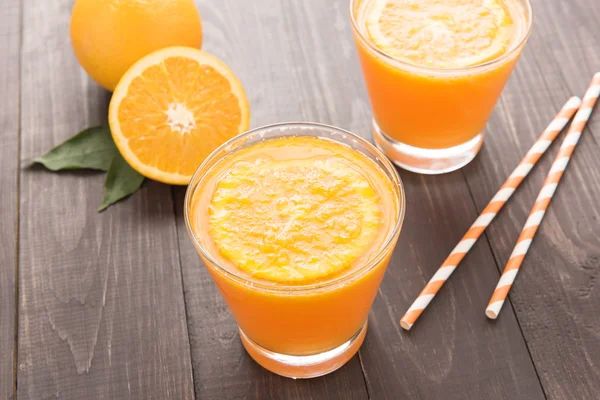 Fresh orange juice and oranges on wooden table — Stock Photo, Image