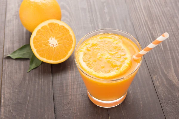 Fresh orange juice and oranges on wooden table — Stock Photo, Image
