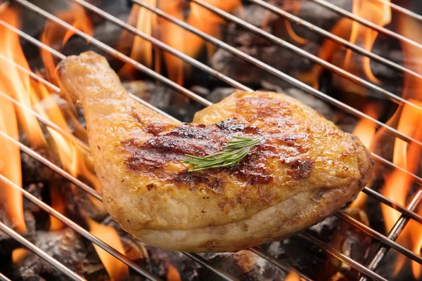 Chicken leg grilling over flames on a barbecue — Stock Photo, Image