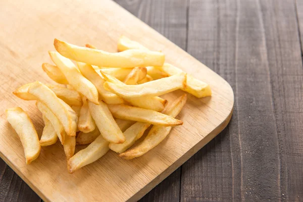 Pommes auf Schneidebrett auf Holztisch — Stockfoto